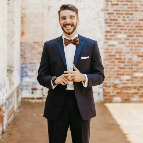 a man in a suit and bow tie holding a glass